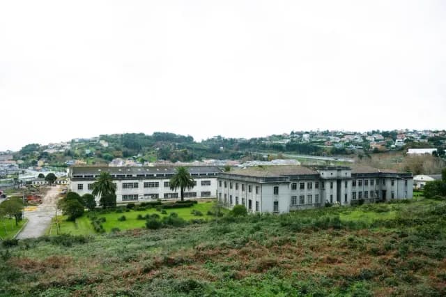 Vista do recinto da Fábrica de Armas antes da rehabilitación, coas súas naves aliñadas e a cidade ao fondo.
