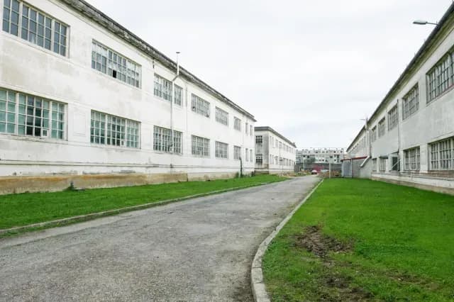 Rúa entre as naves aliñadas do recinto da Fábrica de Armas antes da rehabilitación, cos primeiros edificios a ambos os lados.